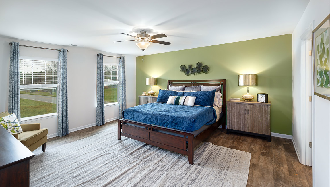Primary bedroom with wood floors, two large windows