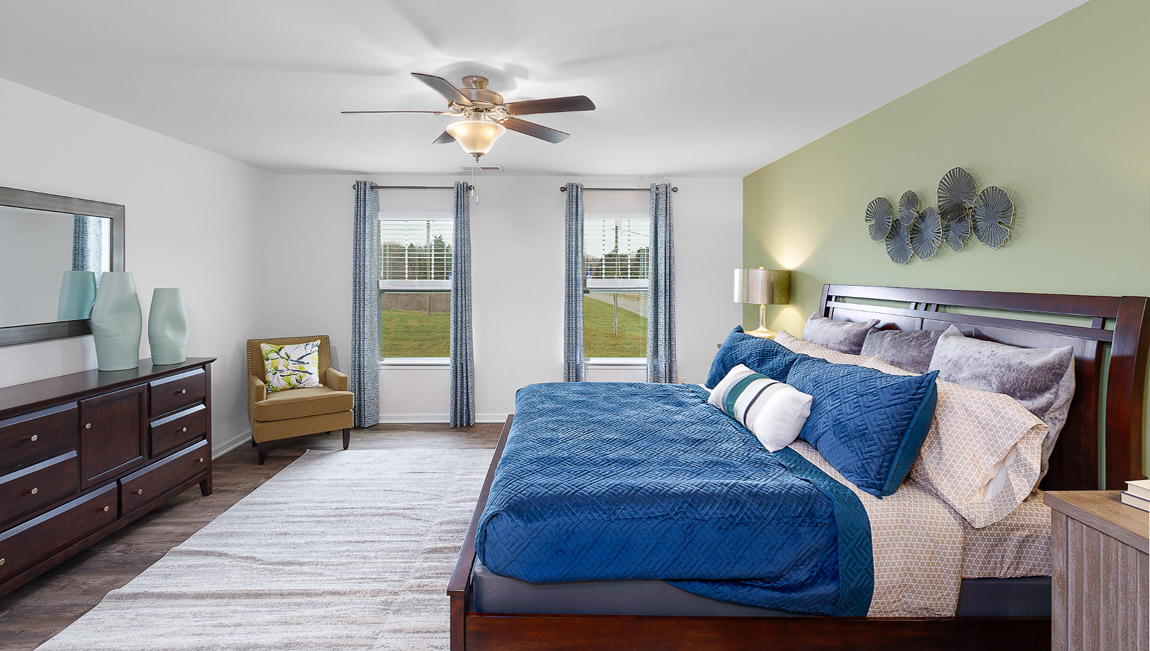 Primary bedroom with wood floors, two large windows