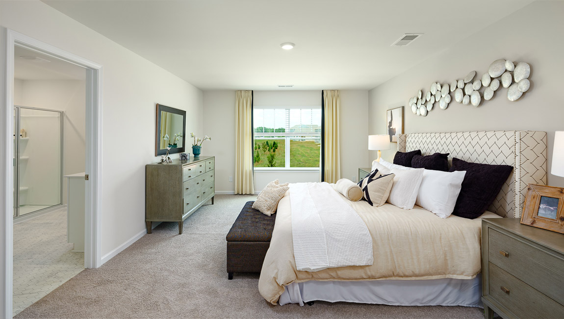 Primary bedroom with large window, carpet and door to bathroom