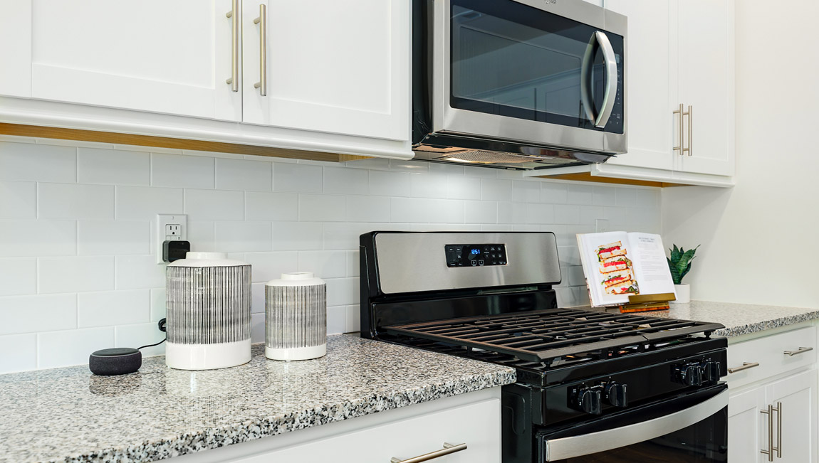 Kitchen and island with white cabinets, breakfast bar area on island, and stainless steel appliances