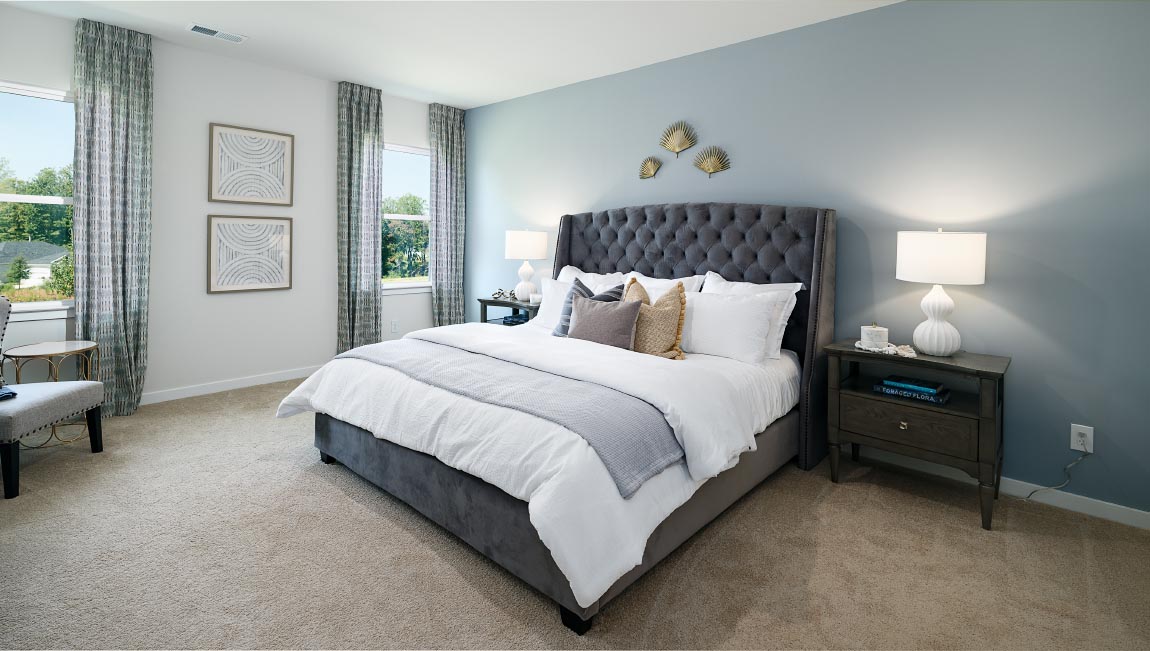 Carpeted primary bedroom with two small windows