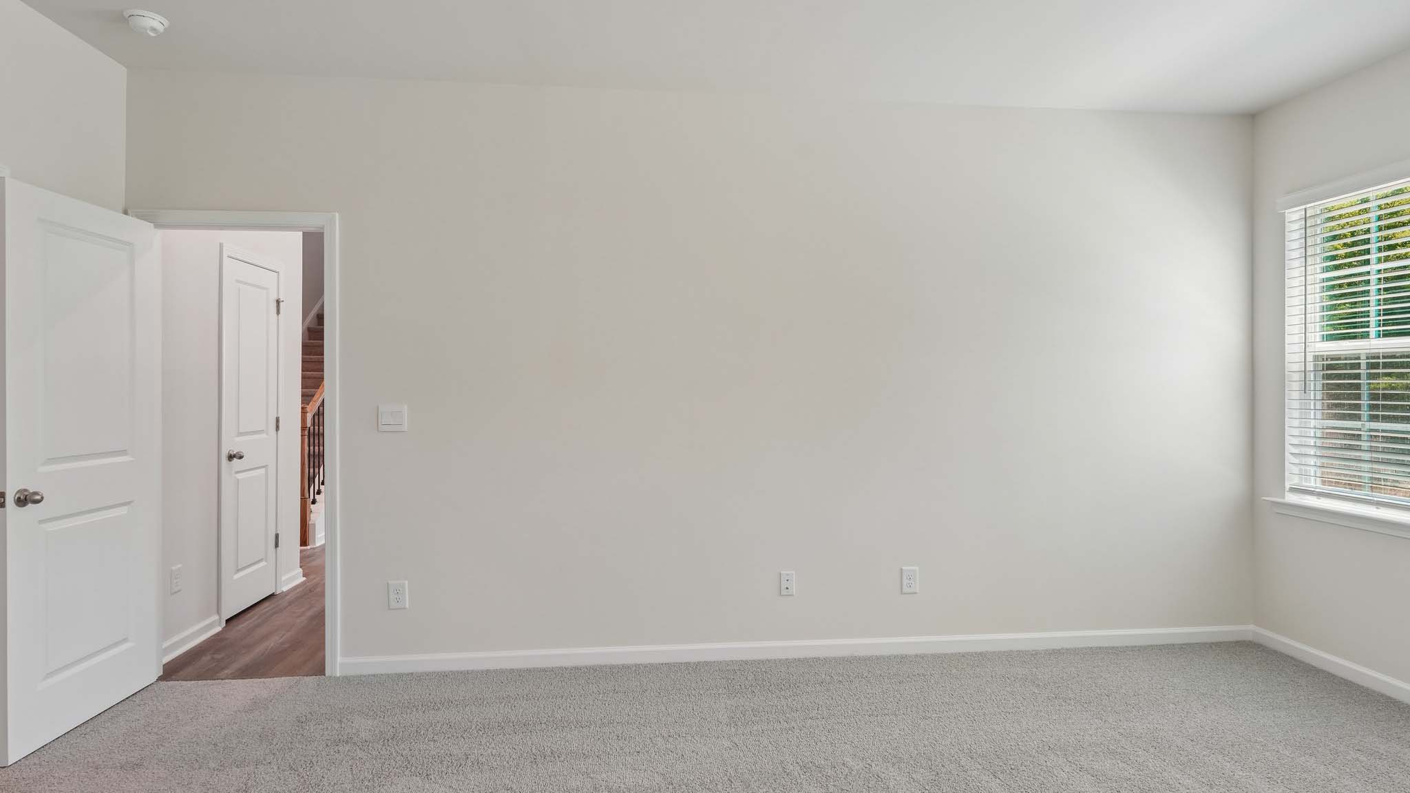 Carpeted primary bedroom with two small windows