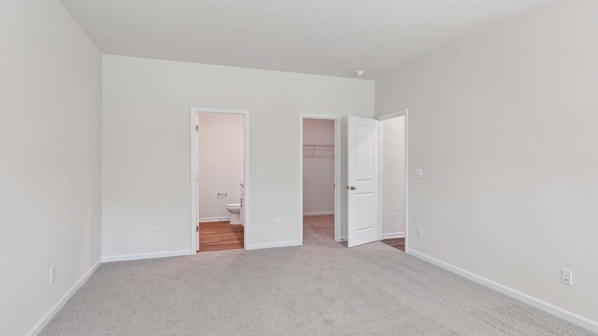Carpeted primary bedroom with two small windows