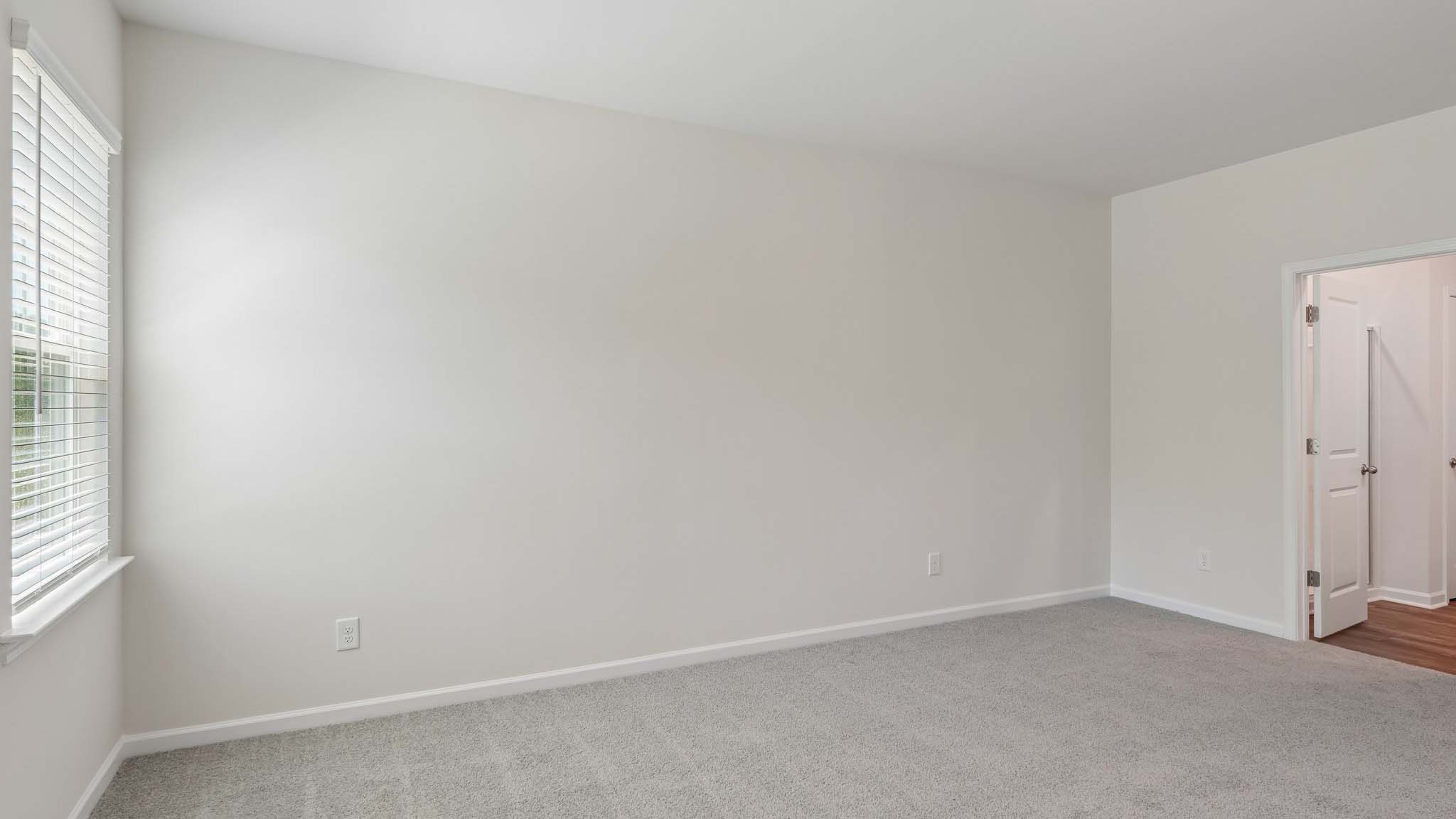 Carpeted primary bedroom with two small windows