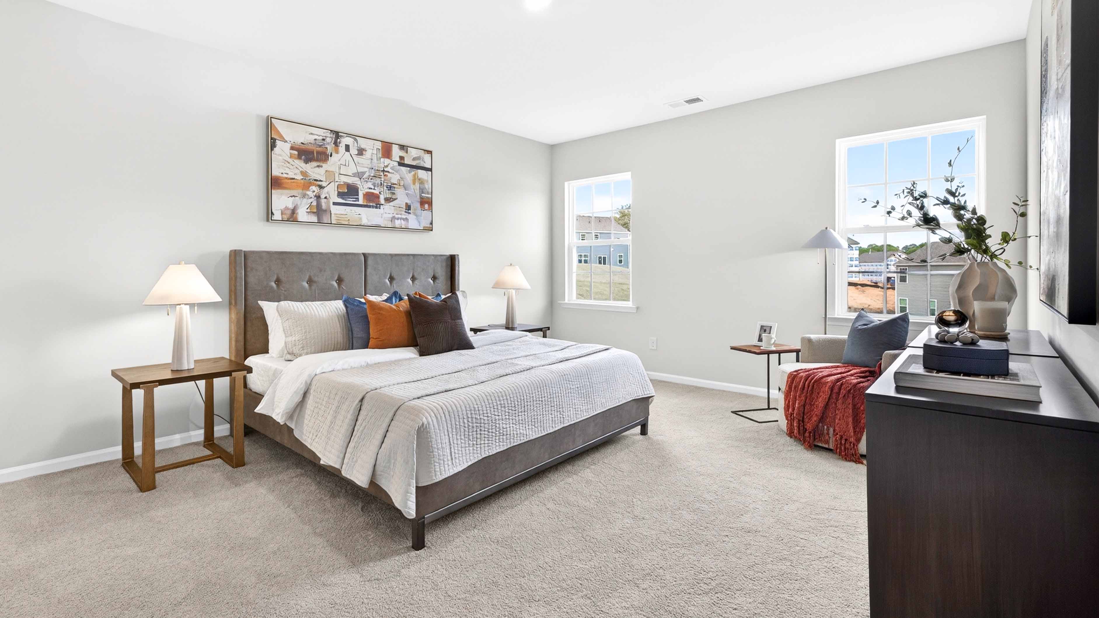 Carpeted primary bedroom with two small windows