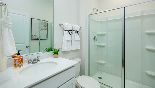 Bathroom with standing glass door shower, and white cabinets