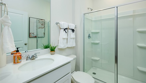 Bathroom with standing glass door shower, and white cabinets