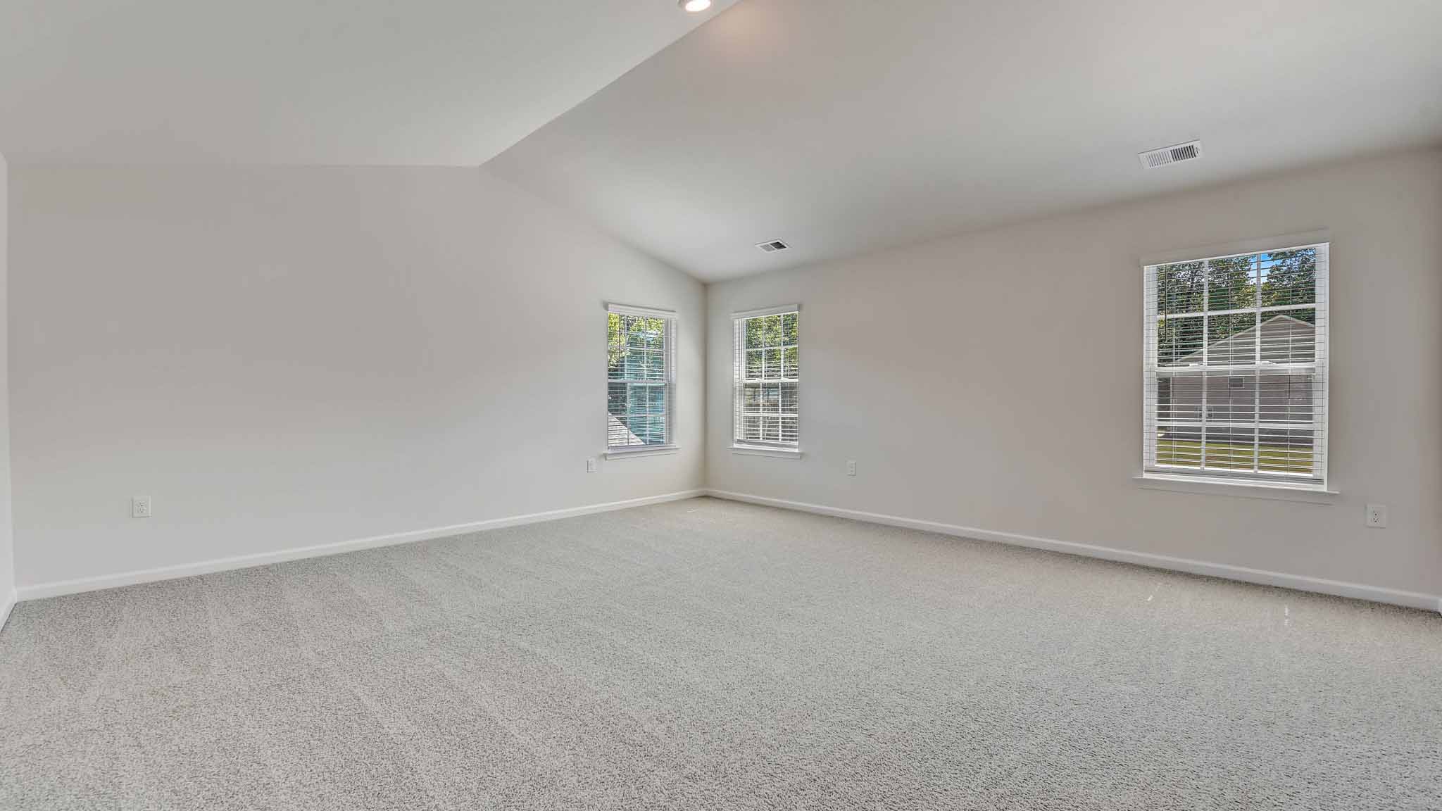Primary carpeted bedroom with large windows