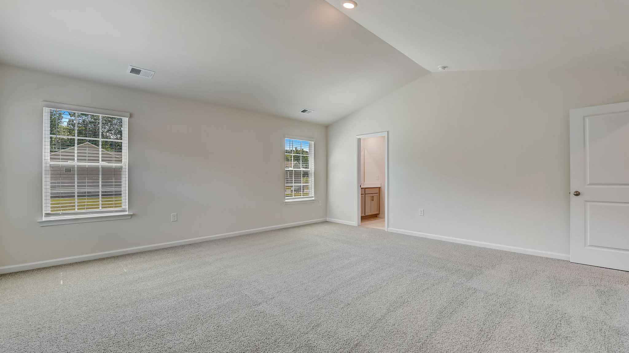 Primary carpeted bedroom with large windows