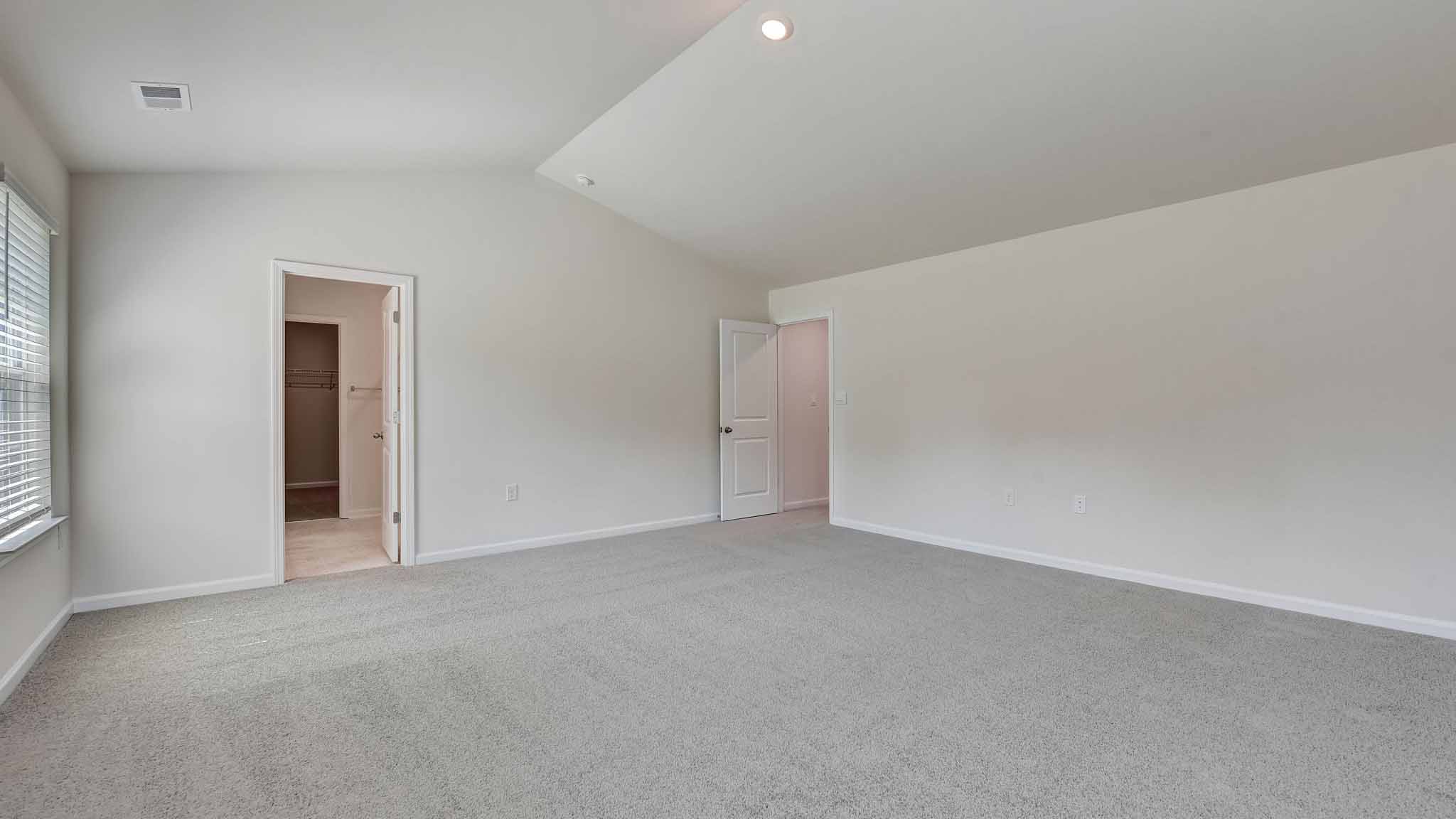 Primary carpeted bedroom with large windows