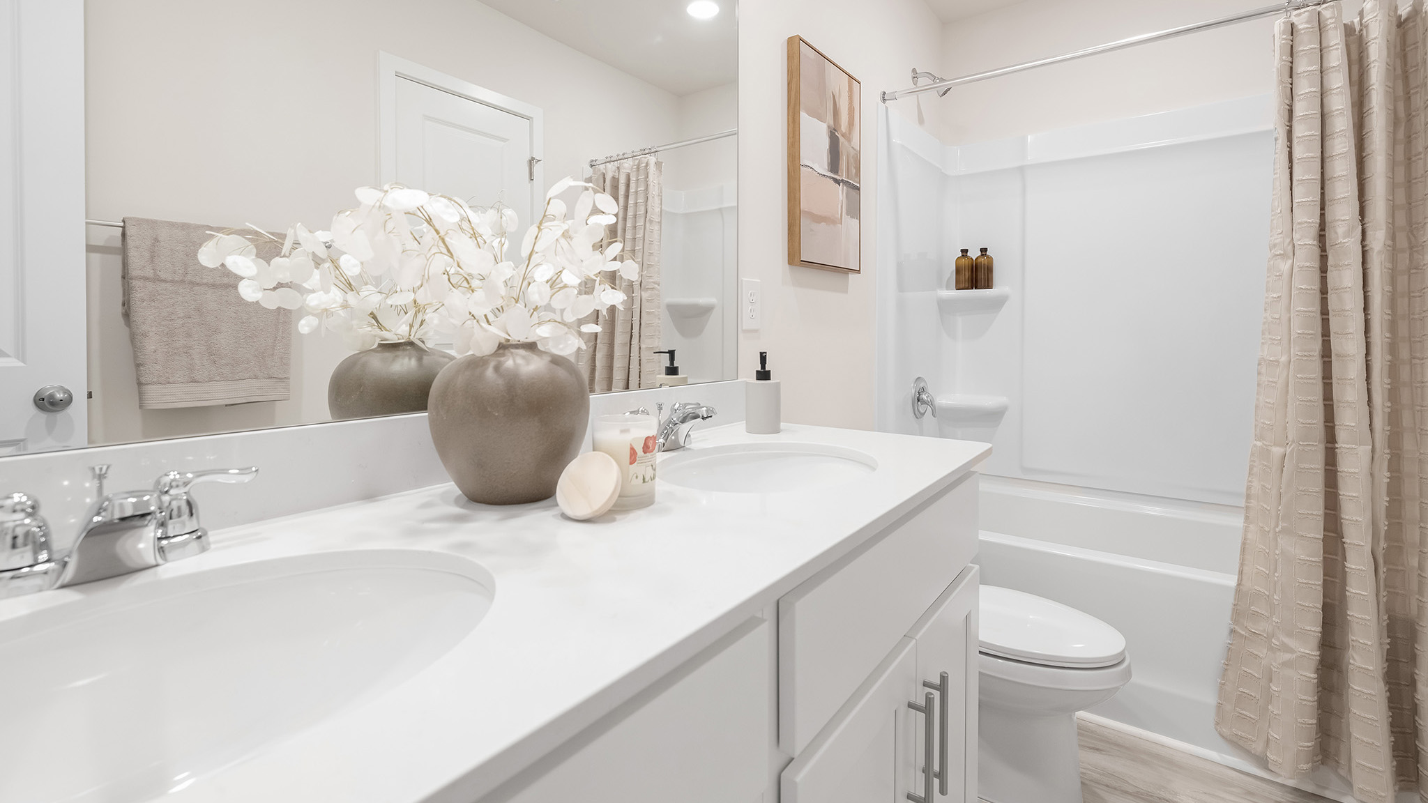 Bathroom with double sinks, bathtub, and white cabinets and counters
