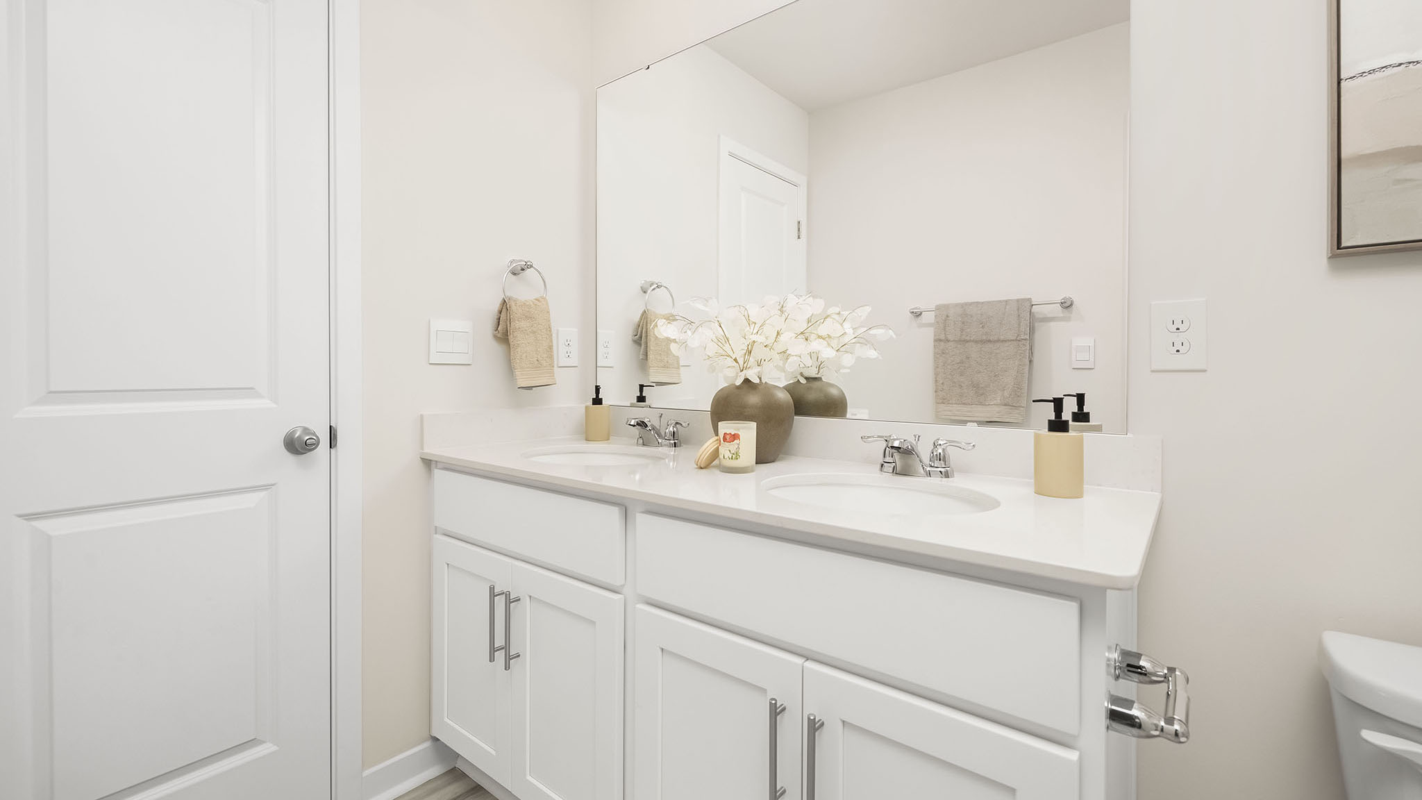 Bathroom with double sinks, bathtub, and white cabinets and counters