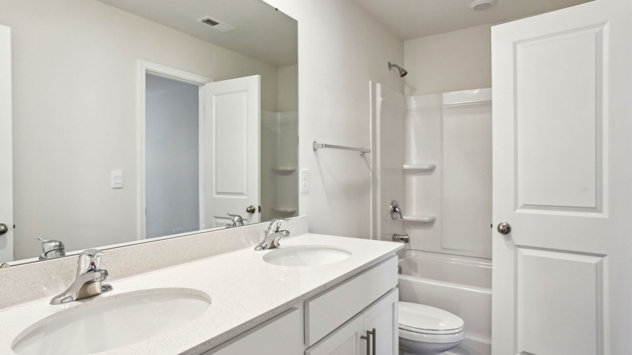 Bathroom with double sinks, bathtub, and white cabinets and counters