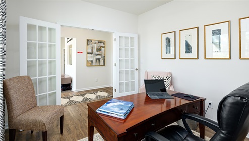 Flex space with large window, being used as office, with french doors at entrance