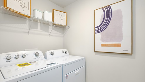 Laundry room with storage racks above machines