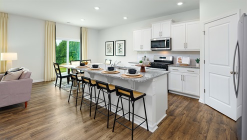 Kitchen and island with white cabinets, breakfast bar area on island, and stainless steel appliances