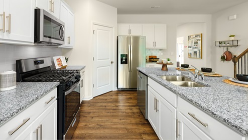 Kitchen and island with white cabinets, breakfast bar area on island, and stainless steel appliances