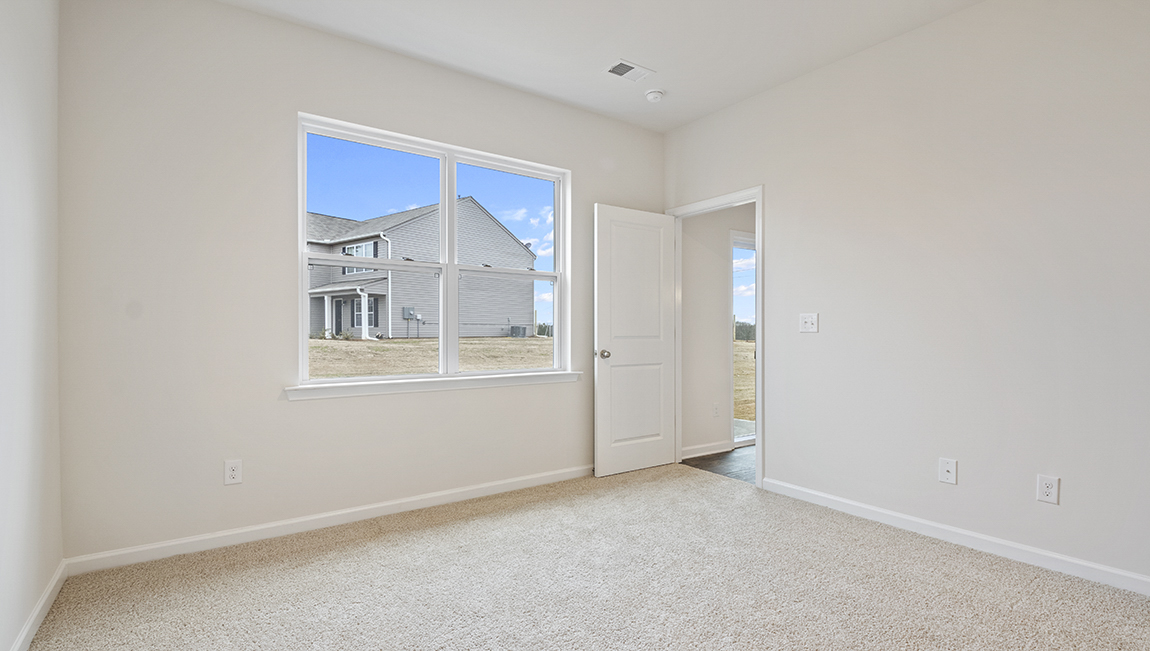 Primary carpeted bedroom with large window