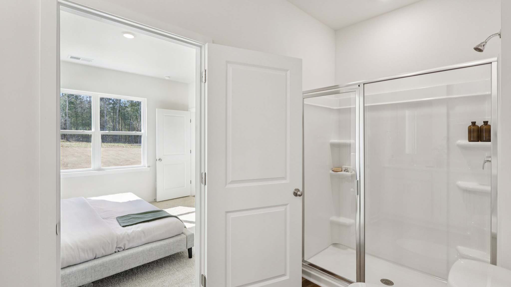 Primary bathroom with white counters and glass door shower