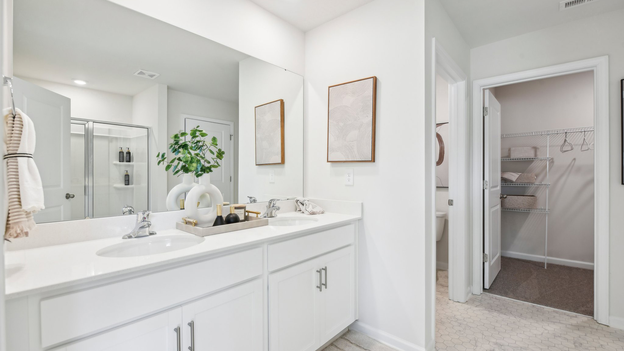 Primary bathroom with double sinks, white cabinets and counters