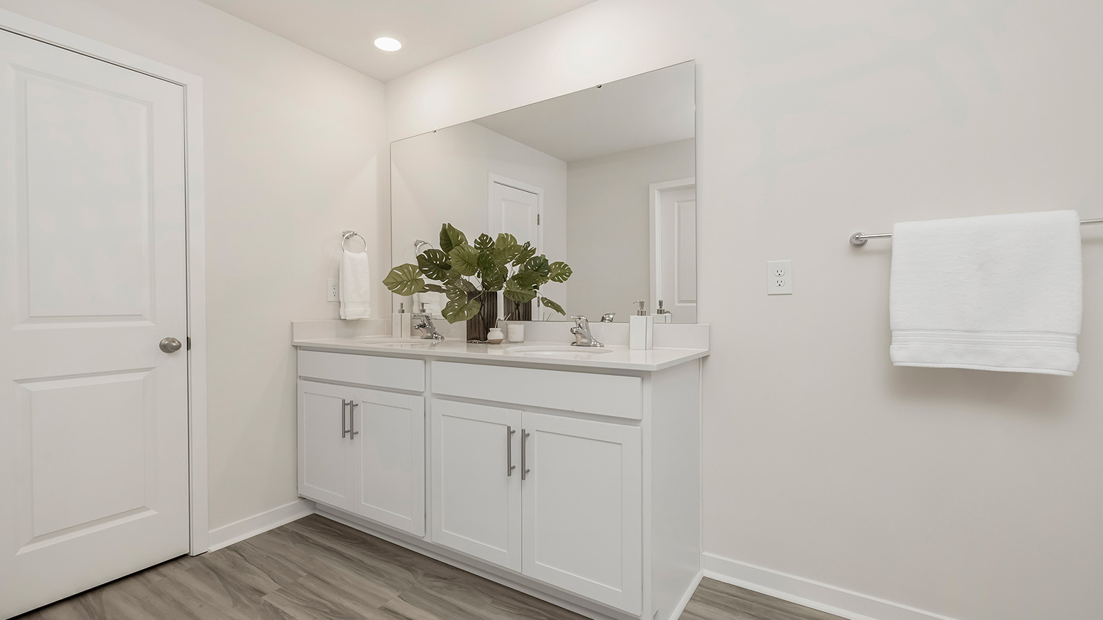 Primary bathroom with double sinks, white cabinets and glass door shower
