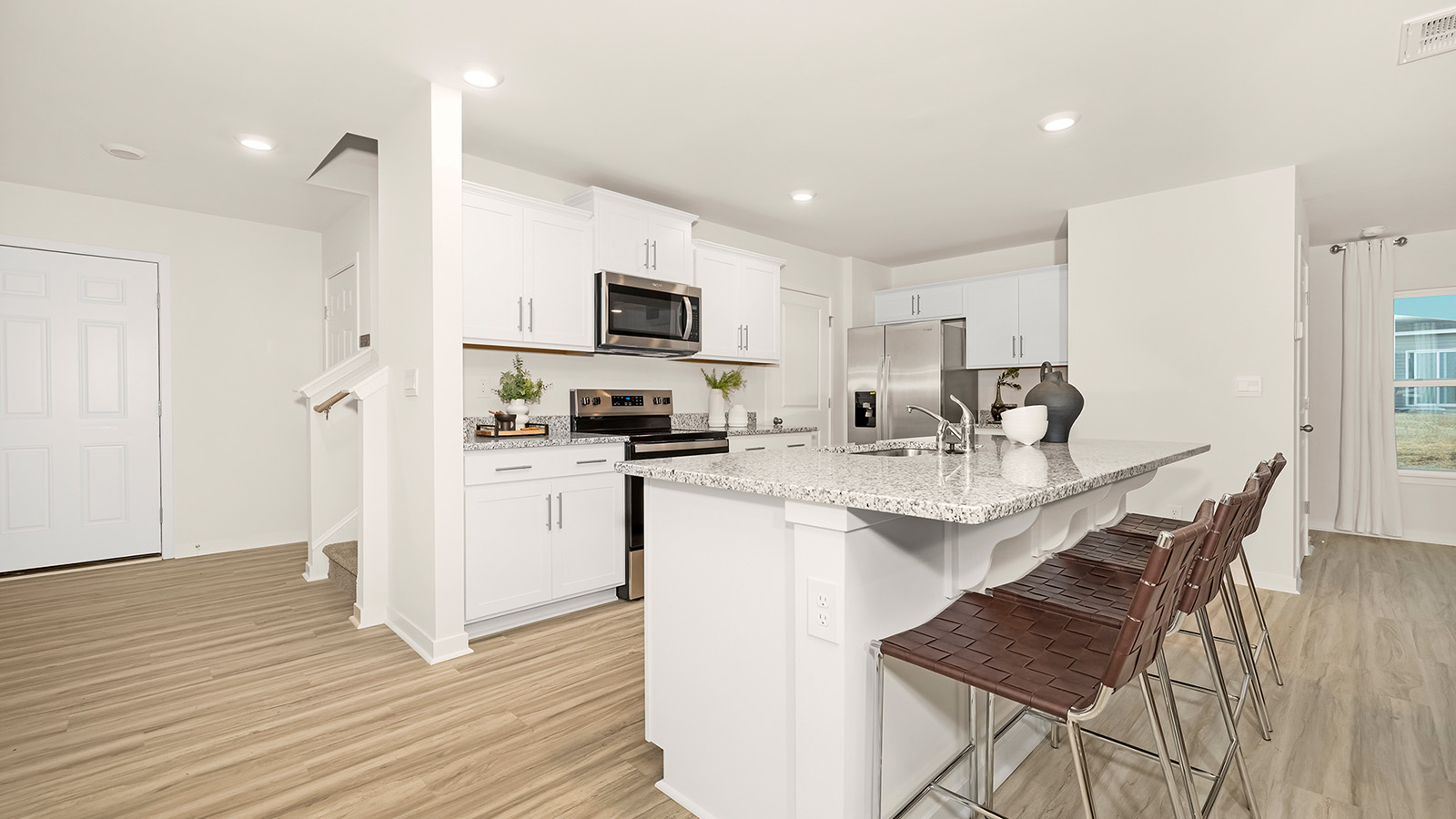 Kitchen and island with white cabinets, white subway tile backsplash and stainless steel appliances