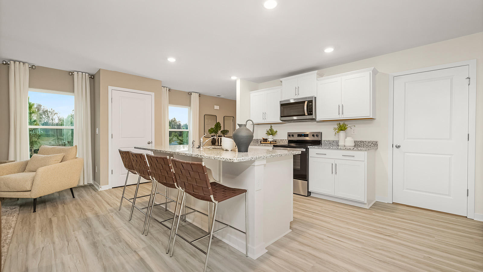 Kitchen and island with white cabinets, white subway tile backsplash and stainless steel appliances