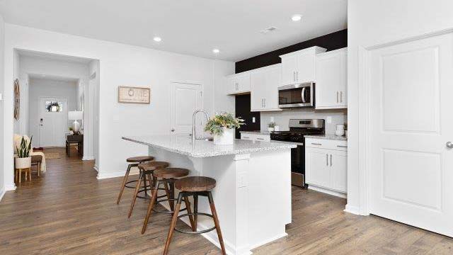 Kitchen and island with white cabinets, quarts countertops, wood floors, and stainless steel appliances