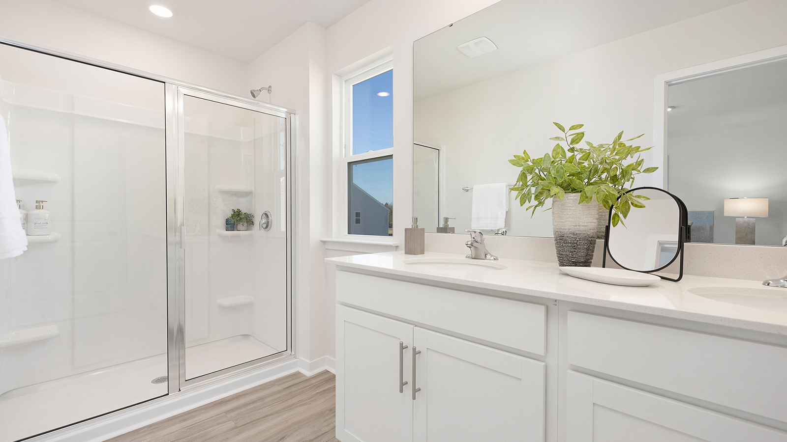 Primary bathroom with white cabinets and standing glass shower