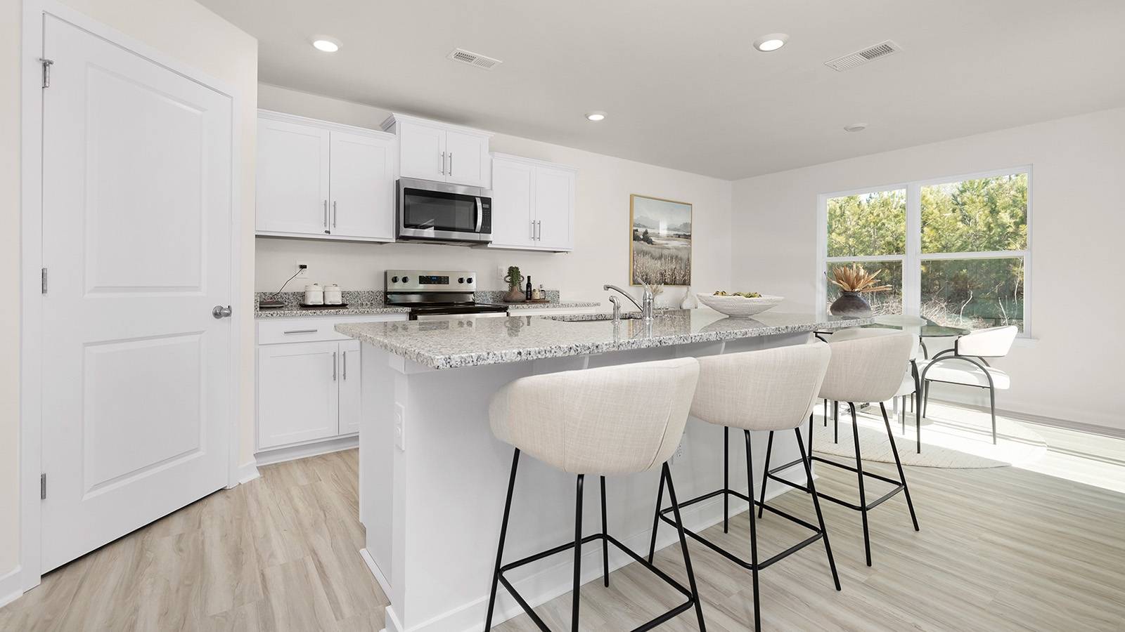 Kitchen and island with white cabinets and stainless steel appliances