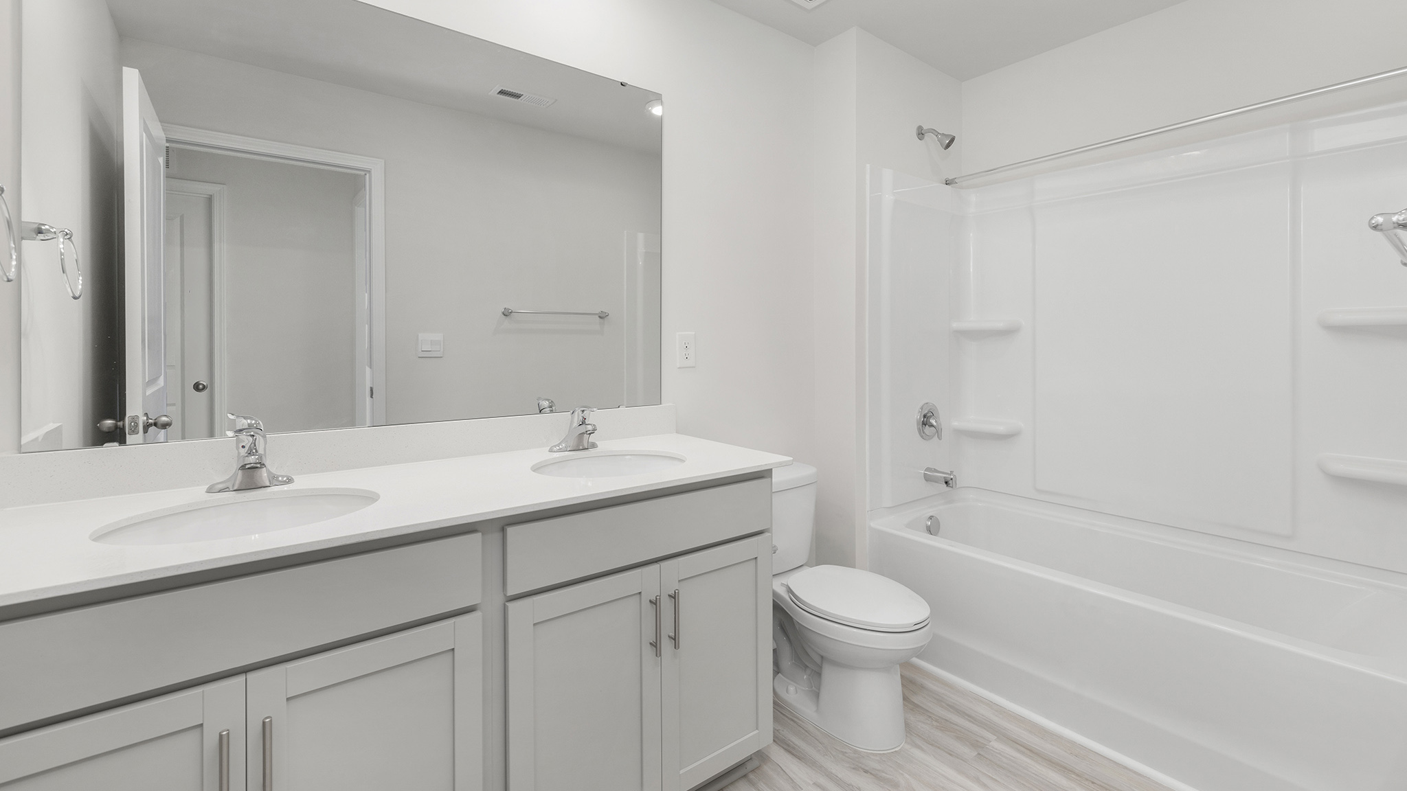 Bathroom with double sinks, white cabinets and counters, and bathtub