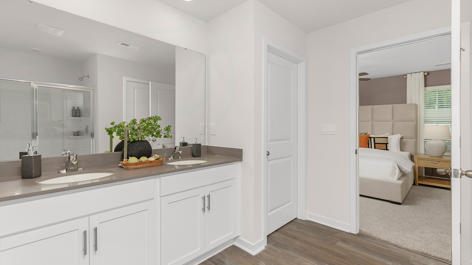 Primary bathroom with double sinks, white cabinets and counters