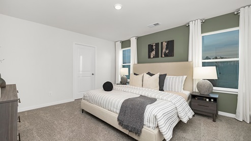 Primary bedroom carpeted with two large windows