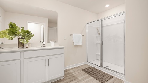 Primary bathroom with double vanity and glass door shower