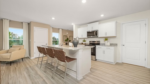 Kitchen with large island with white countertops and cabinets and stainless steel appliances