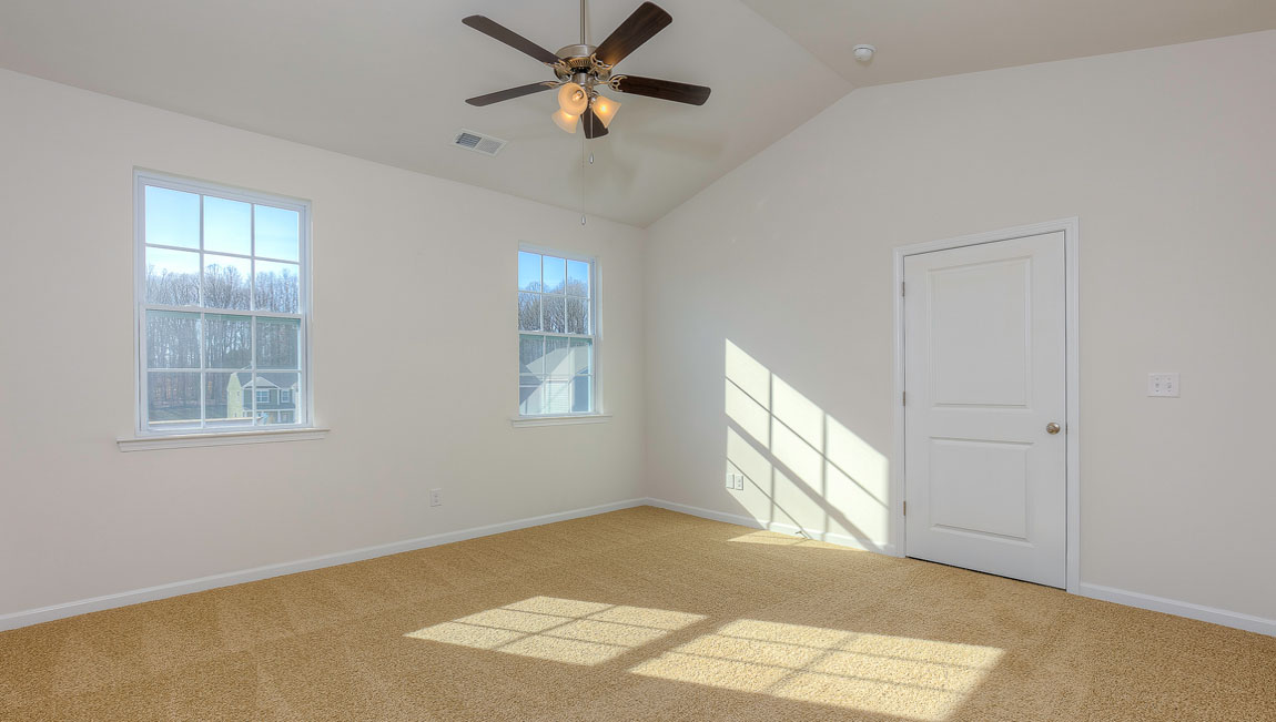 Primary carpeted bedroom with windows
