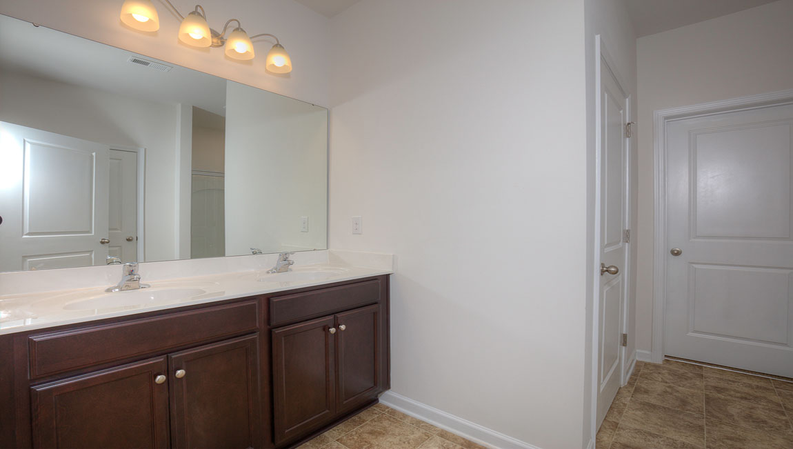 Primary bathroom with double sinks, standing glass shower, and toilet