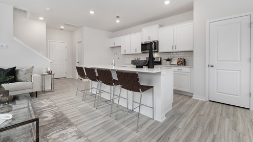 Open concept kitchen with large island, white cabinets and countertops, and stainless steel appliances
