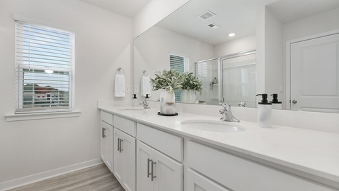 Primary bathroom with double vanity and glass door shower