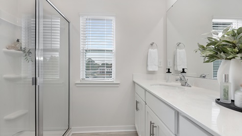 Primary bathroom with double vanity and glass door shower