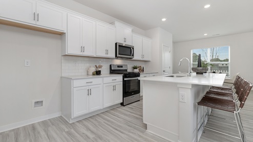 Open concept kitchen with large island, white cabinets and countertops, and stainless steel appliances