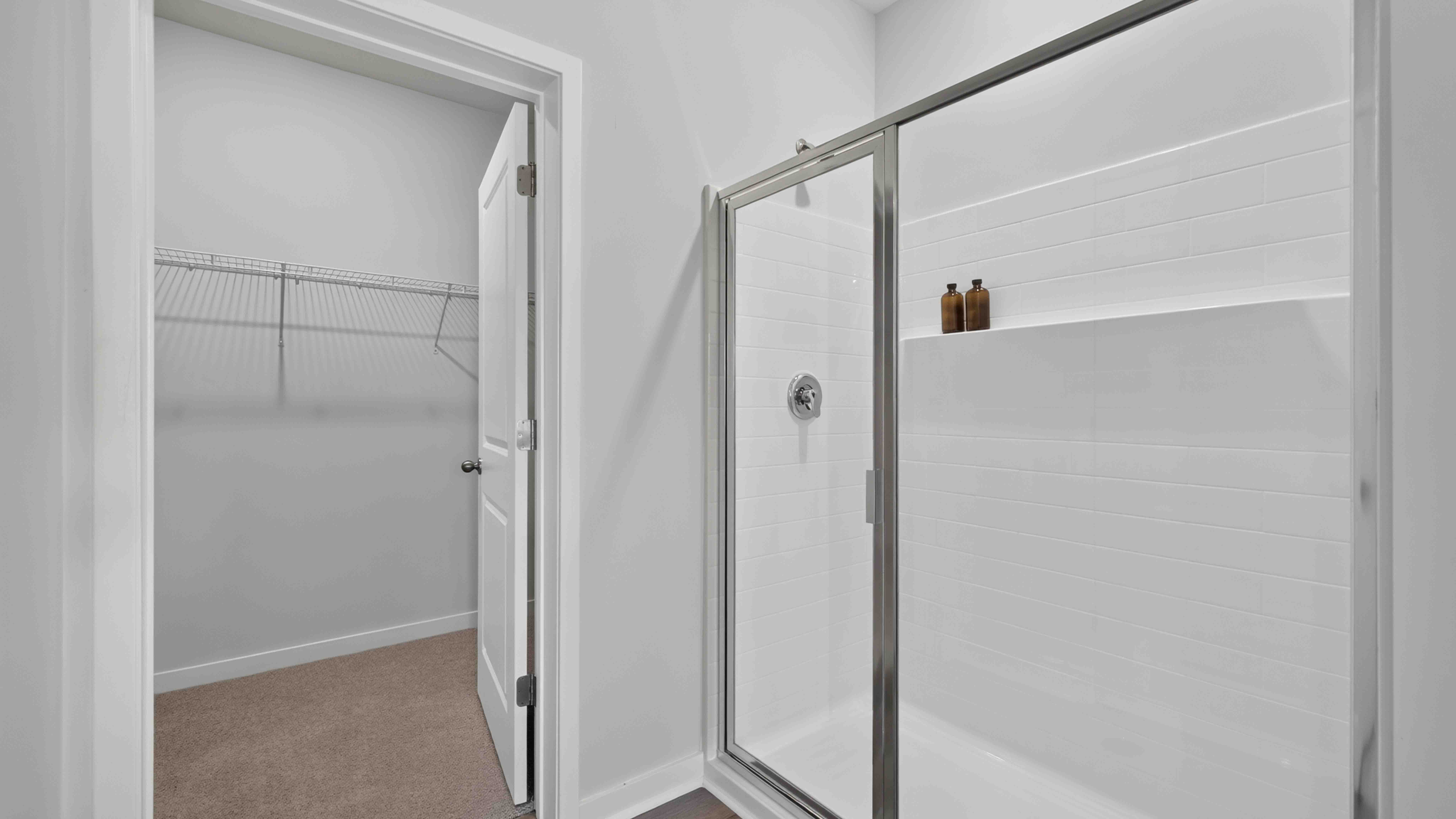 Primary bathroom with double sinks, standing glass shower, and toilet