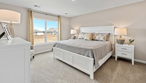 Primary bedroom with carpet and window.
