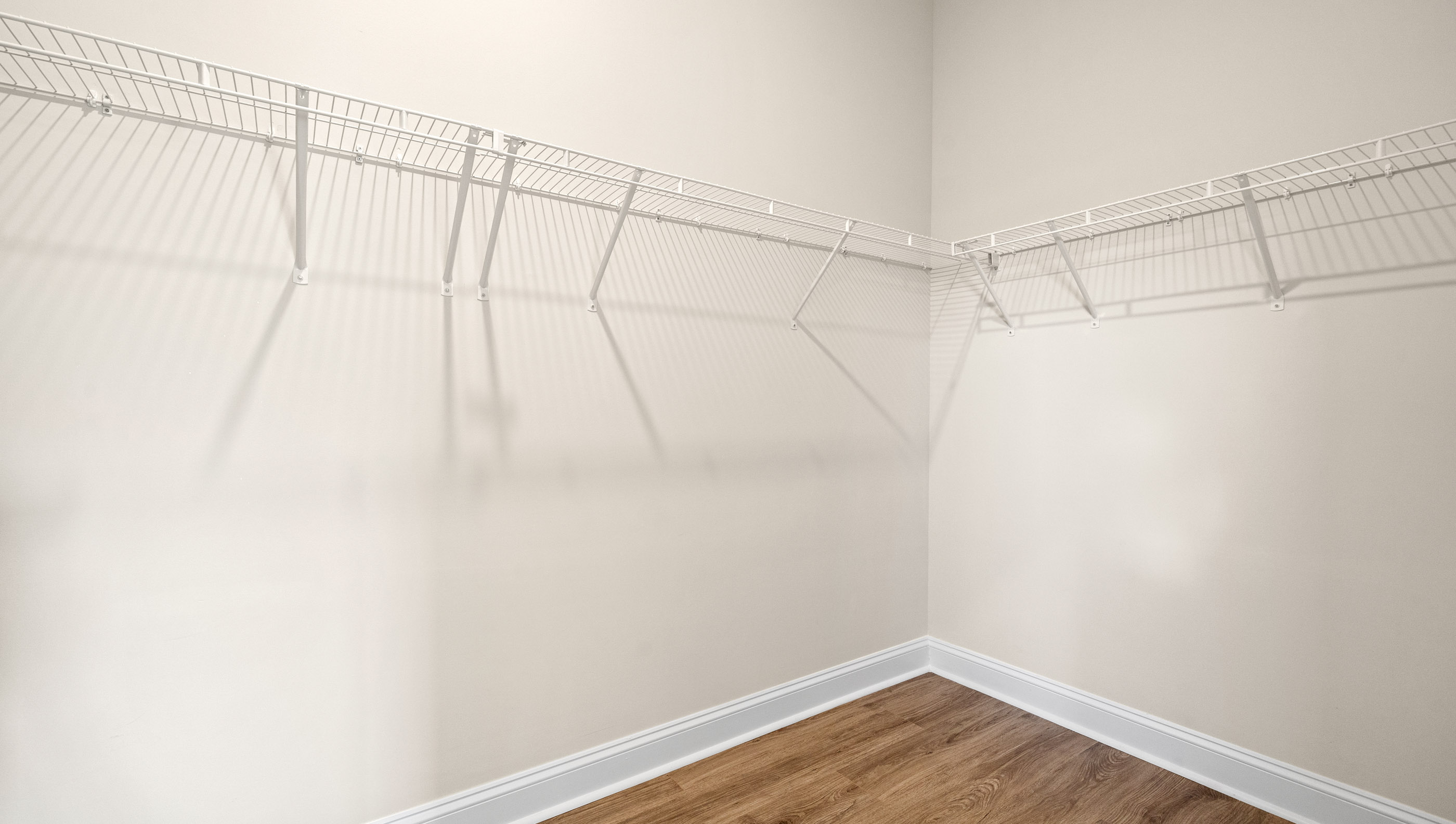 Primary walk in closet with hanging shelves.
