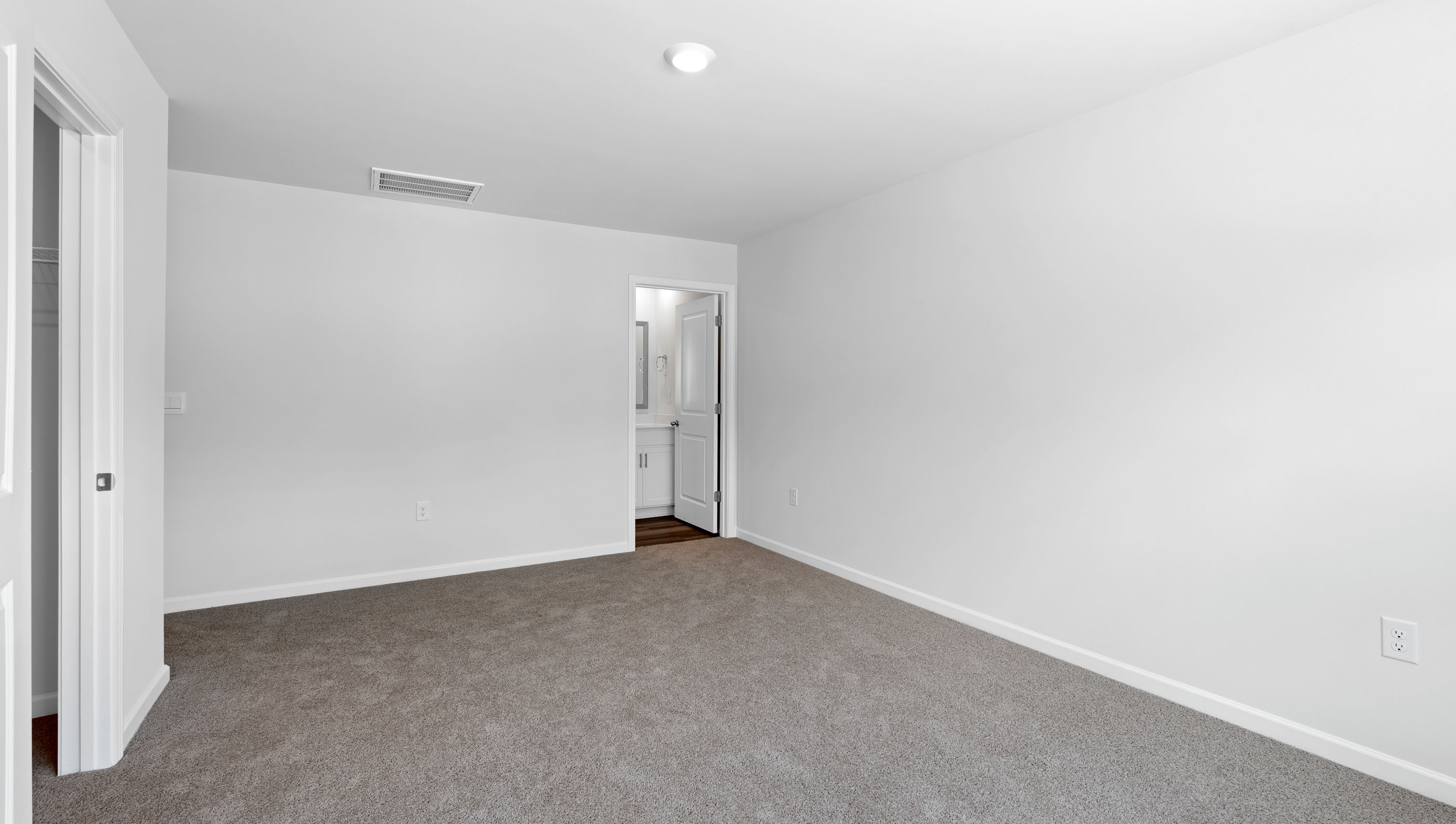 Primary bedroom with large window and carpet.
