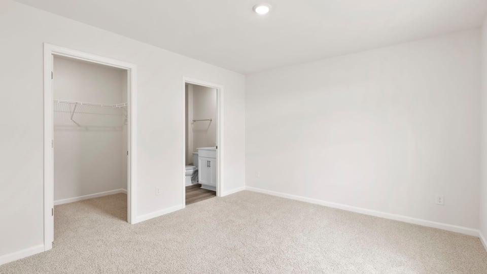 Primary bedroom with carpet and windows.