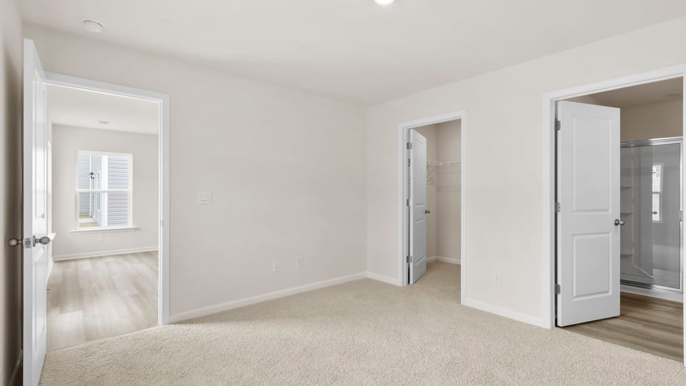 Primary bedroom with carpet and windows.