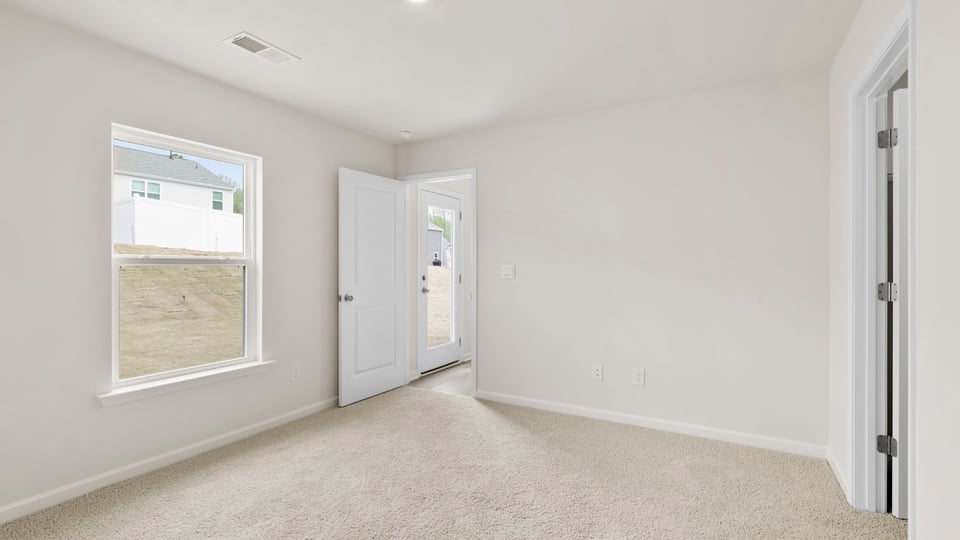 Primary bedroom with carpet and windows.