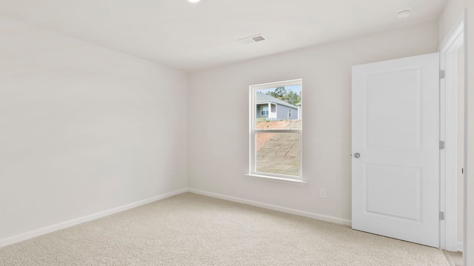 Primary bedroom with carpet and windows.