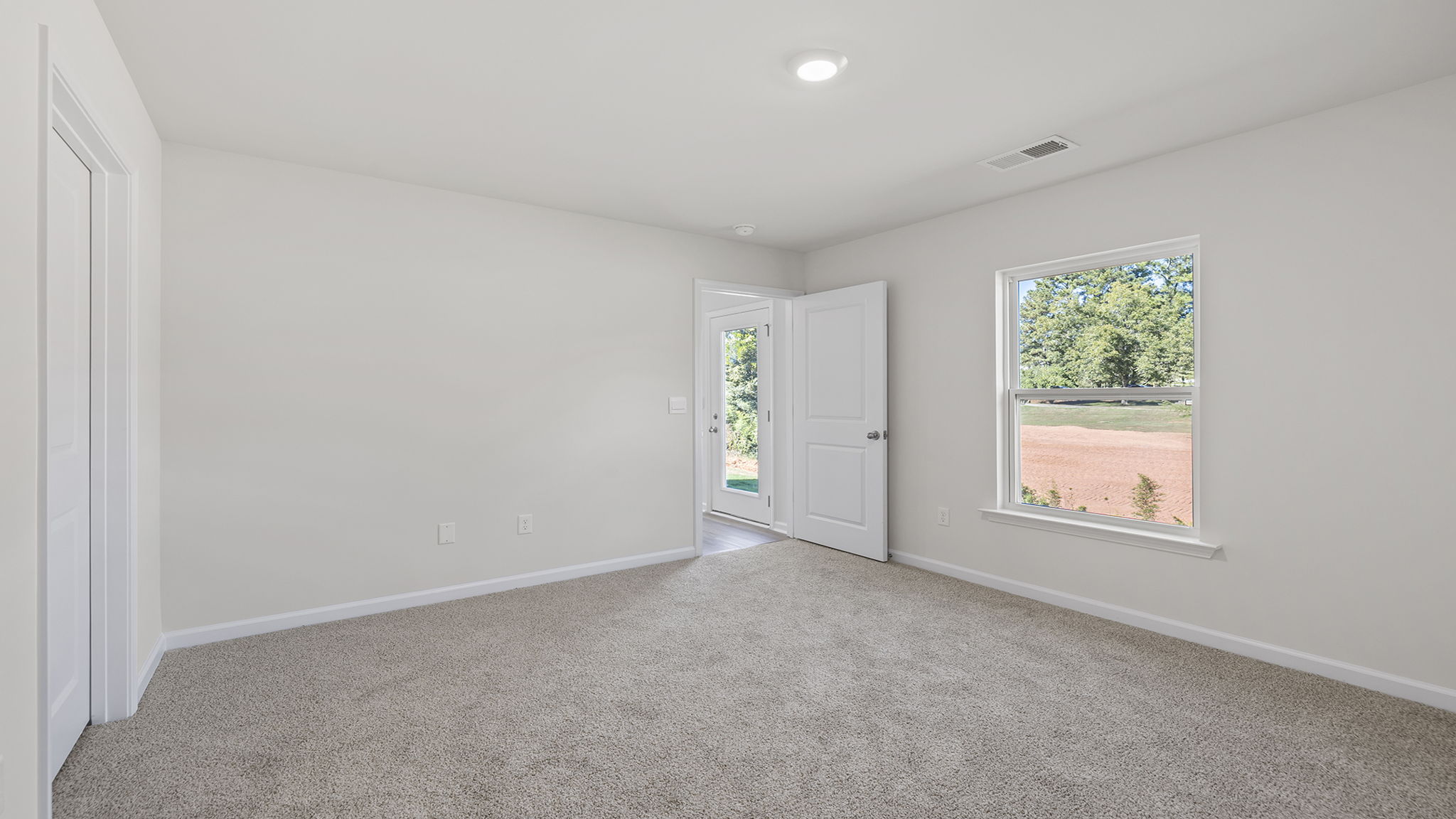 Primary bedroom with windows and carpet.